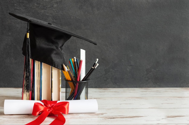 Academic cap and graduation diploma scroll and tied with red ribbon