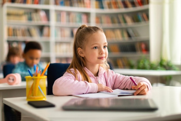 Academic concept smart caucasian school girl sitting at desk in classroom listening teacher and