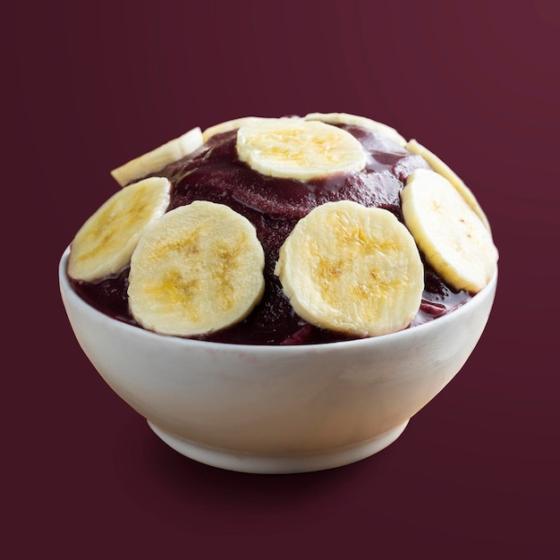 Acai Brazilian frozen acai berry ice cream bowl with banana slices Isolated on purple background