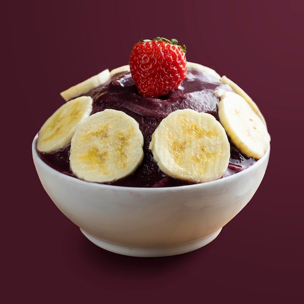 Acai Brazilian frozen acai berry ice cream bowl with banana slices and strawberry Isolated on purple background