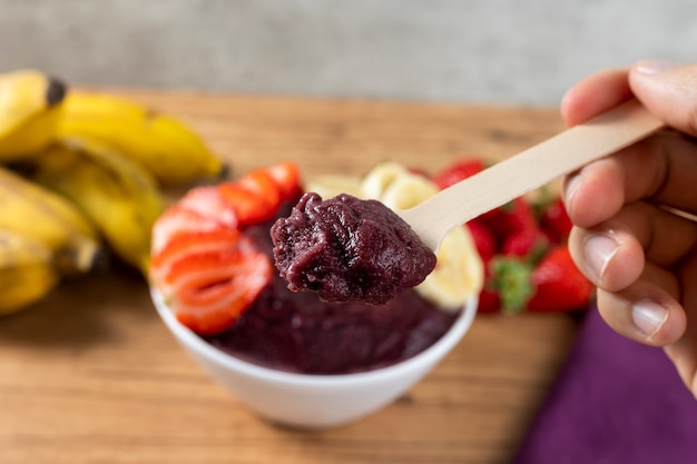 Acai, Brazilian frozen Acai berry ice cream bowl with strawberries and bananas. with fruits on wooden table. Summer menu front view