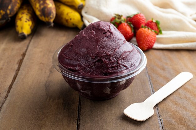 Acai, Brazilian frozen Acai berry ice cream bowl with strawberries and bananas. with fruits on wooden table. Summer menu front view