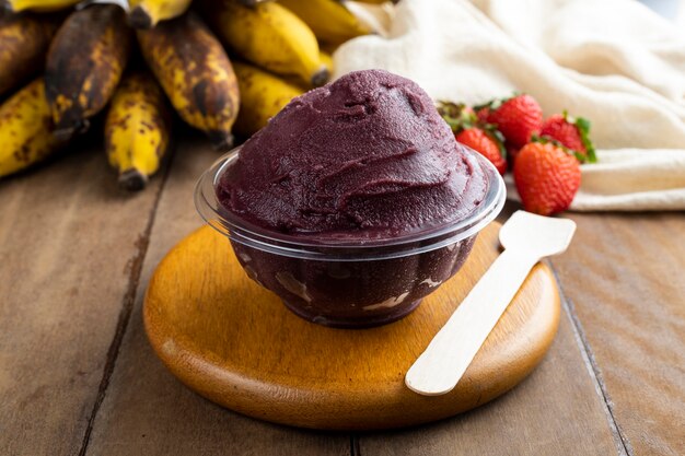 Acai, Brazilian frozen Acai berry ice cream bowl with strawberries and bananas. with fruits on wooden table. Summer menu front view