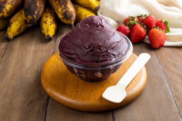 Acai, Brazilian frozen Acai berry ice cream bowl with strawberries and bananas. with fruits on wooden table. Summer menu front view