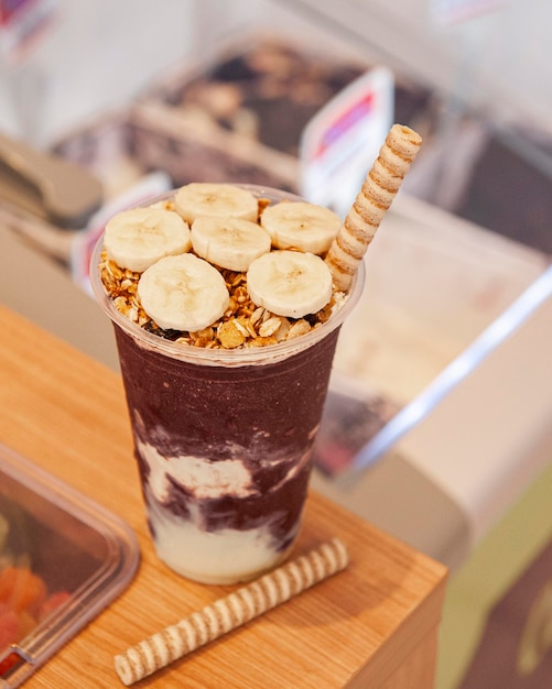 Acai ice cream cup with banana and granola on top of ice cream counter Copy space