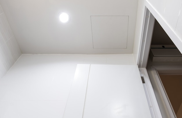 The access door on the white ceiling in the bathroom for maintenance of the electric system