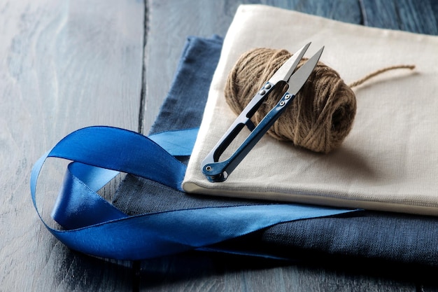 Accessories for sewing and needlework thread and fabric scissors on a dark blue wooden background