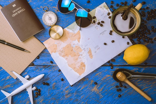 Accessories for the traveler on the old background on the on blue wood table. Travel concept using world map and compass along with other travel accessories. Hot coffee and beans. summer