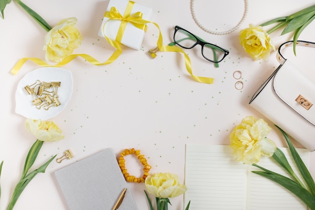 Accessories for a woman blogger on a light background with a handbag spring flowers yellow tulips