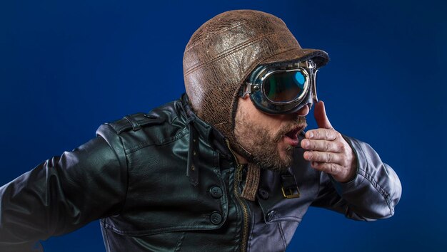 Accident, pilot of the 20s with sunglasses and vintage aviator helmet. Wears leather jacket, beard and expressive faces