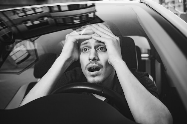 Accident. Young caucasian man driving a car shocked about to have traffic accident