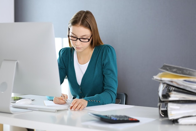 Accountant checking financial statement or counting by calculator income for tax form hands closeup Business woman sitting and working at the desk in office Audit concept