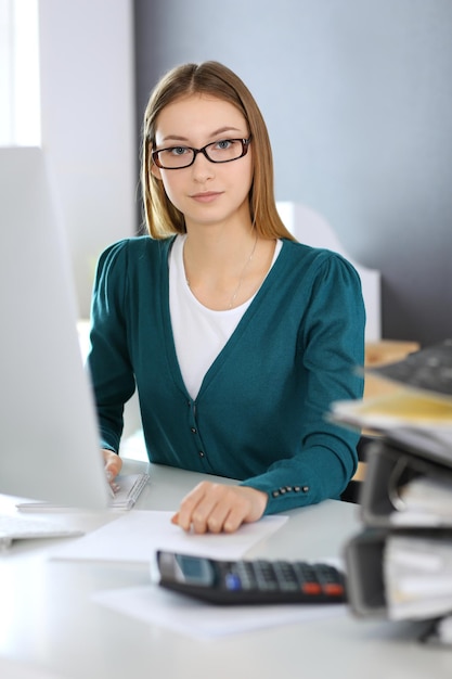 Photo accountant checking financial statement or counting by calculator income for tax form hands closeup business woman sitting and working at the desk in office audit concept