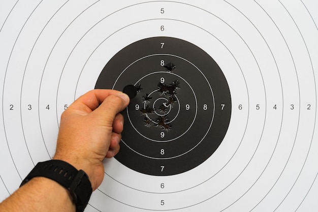 Photo accurate shooting at a shooting range a mans hand seals bullet holes in the center of a paper targe