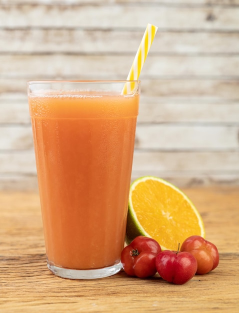 Acerolas or Barbados Cherries and orange juice with fruits over wooden table