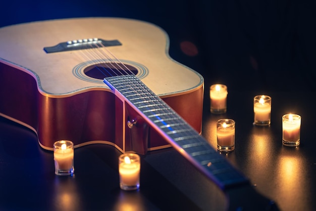 Acoustic guitar on a black background with candles