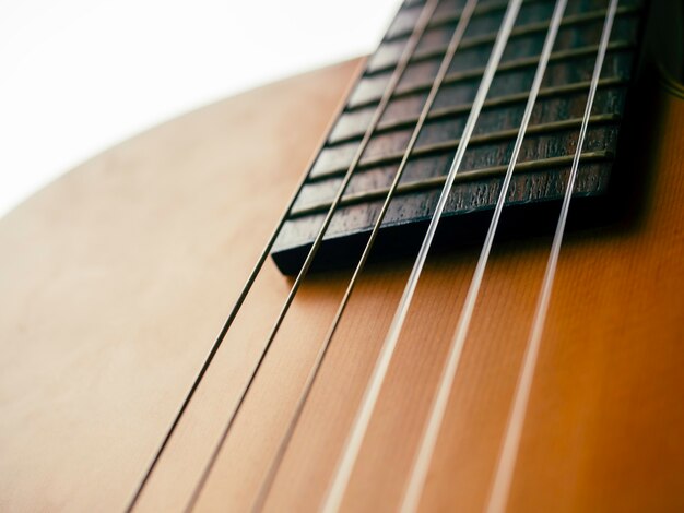 Acoustic guitar body without sound hole background. Close up of six strings on fingerboard and fret on brown wooden electric classical guitar.