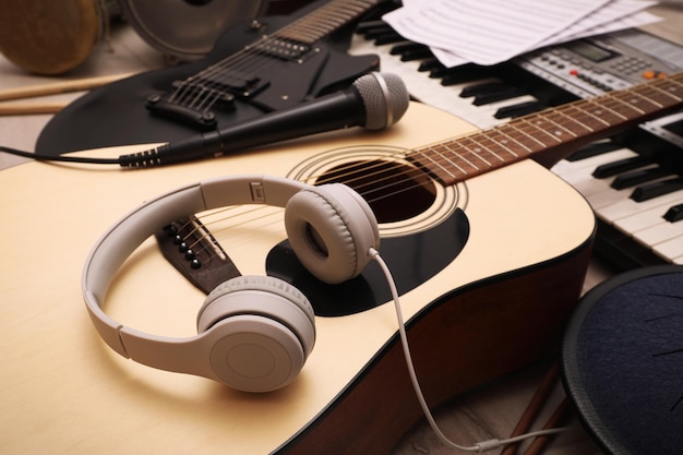 Acoustic guitar headphones and microphone on wooden background closeup