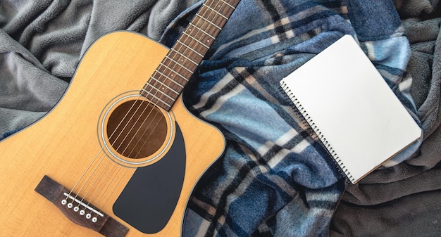 Acoustic guitar and notepad on a plaid background top view