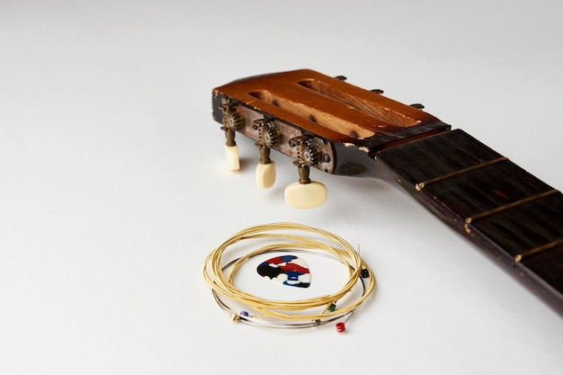 Acoustic guitar strings and pick on white background closeup