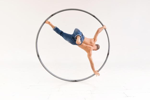 Acrobat performing a one leg handspring on cyr wheel