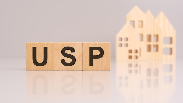 Acronym usp stands for unique selling proposition on wooden cubes with models house on background