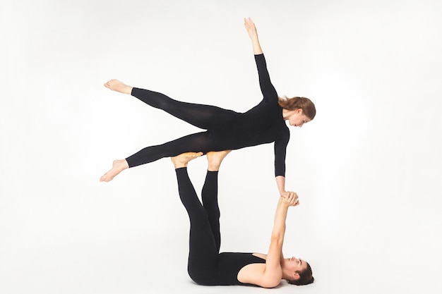 Acroyoga concept, fly pose. Young man holding woman and balancing. Studio shot, isolated on white background