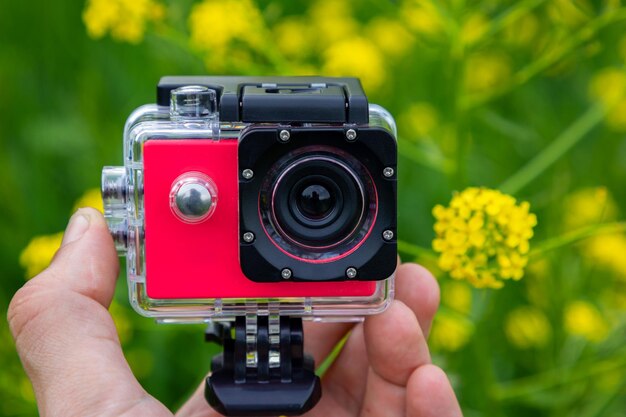 Action camera in hands on a green background with flowers