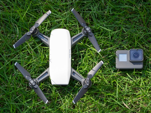 The action camera together with the quadcopter lies on a green grass. top down view.