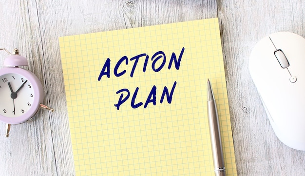 ACTION PLAN text written in a notebook lying on a wooden work table 