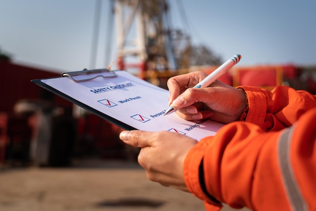 Action of safety officer is writing on safety checklist document during safety audit and inspection