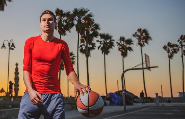 Action shot of young man playing basketball outdoors.