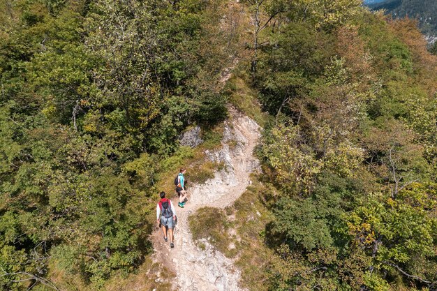 Active couple walking on the hiking trail through the forest enjoying the view from a mountain range