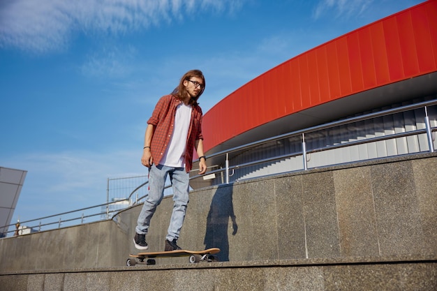 Active energetic stylish hipster guy riding skateboard on city street