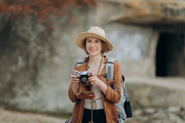 Active healthy Caucasian woman taking pictures with an vintage film camera on a forest rocks