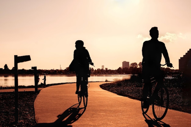 Active leisure in the city at sunset silhouettes of a woman and a man on a bicycle