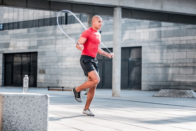 Active lifestyle. Hard working athletic man jumping on a skipping rope while having a workout