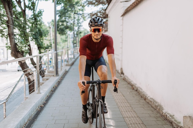 Active male athlete in sport clothes spending summer day for outdoors training on black bike Professional cyclist having regular workout on fresh air