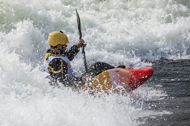 An active male kayaker rolling and surfing in rough water