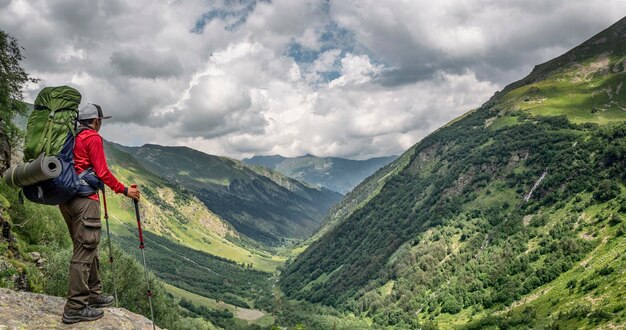 Active man with backpack and camping equipment at Imereteinka river valley background