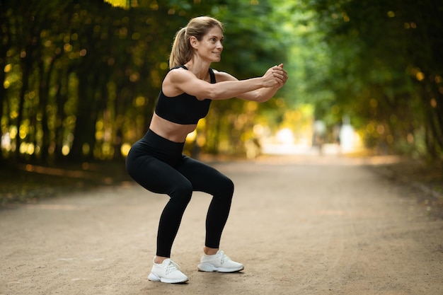 Active middle aged woman training at public park copy space