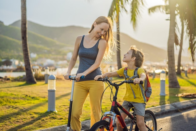 Active school kid boy and his mom riding a bike with backpack on sunny day Happy child biking on way to school Safe way for kids outdoors to school