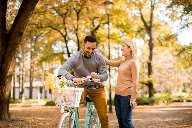 Active senior couple together enjoying romantic walk with bicycle in golden autumn park