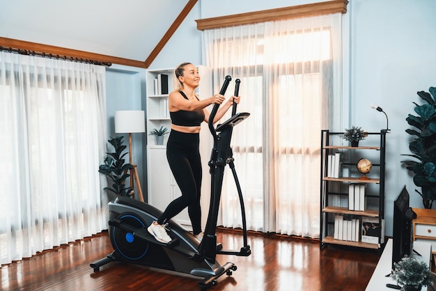 Active senior woman running on elliptical running machine at home portrait in full body shot as fitness healthy lifestyle and body care after retirement for pensioner Clout