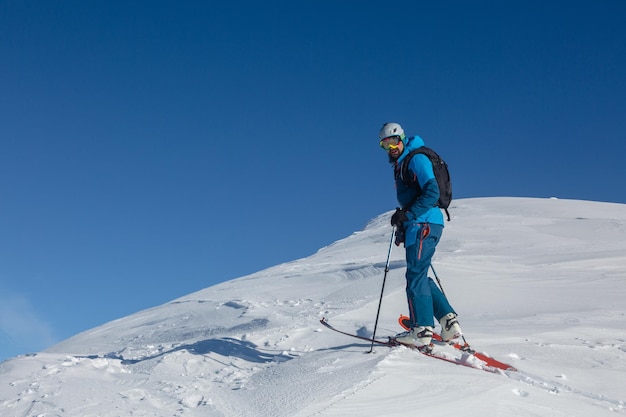 An active skitour rider on a winter trail in the middle of the mountain range