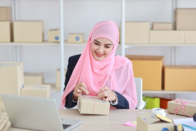 Active smiling asian muslim woman in blue suit sitting and working