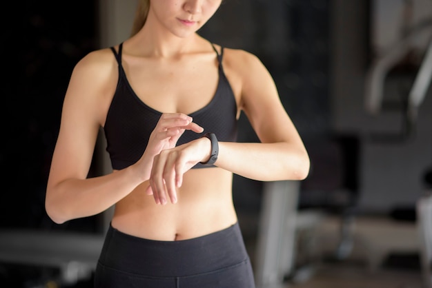 An active woman is using smart watch in fitness gym. Fitness and technology concept .