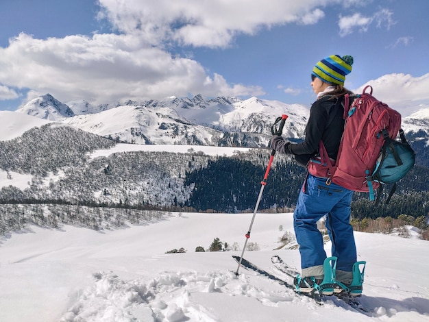 Active woman ski touring on splitboard and looking at panoramic winter mountains background