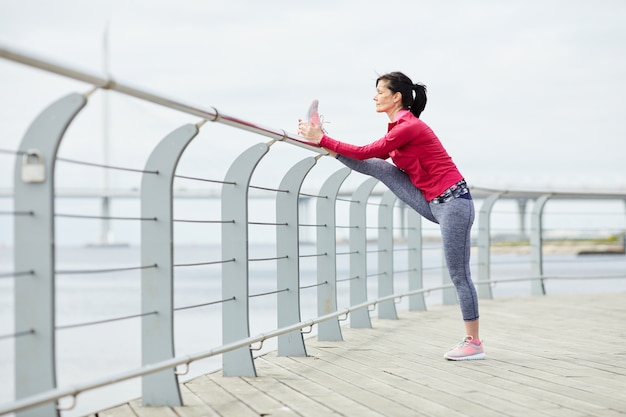 Active Woman Stretching on Pier