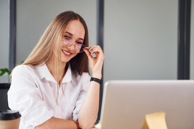 Active working Young adult woman in formal clothes is indoors in the office